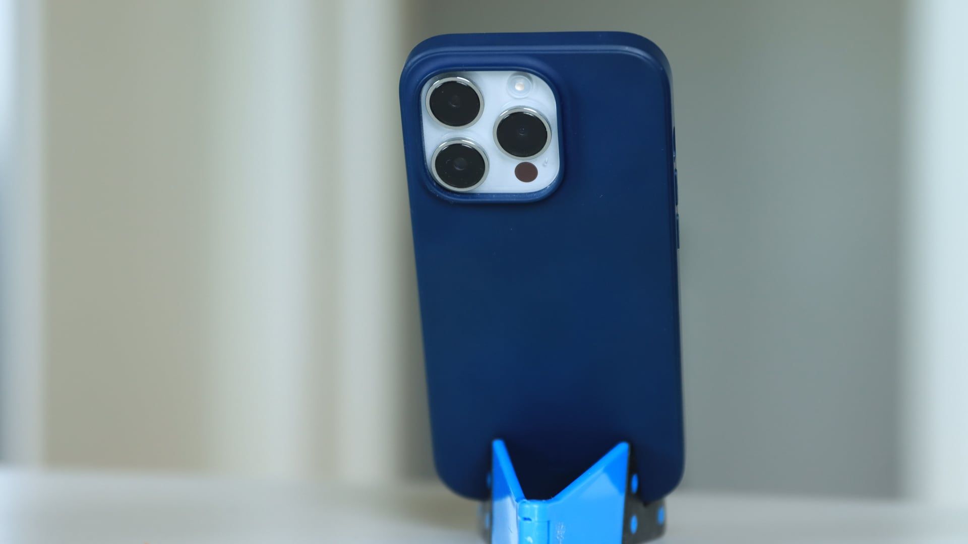 Een smartphone in een blauwe 3D-geprinte telefoonhouder op een wit bureau