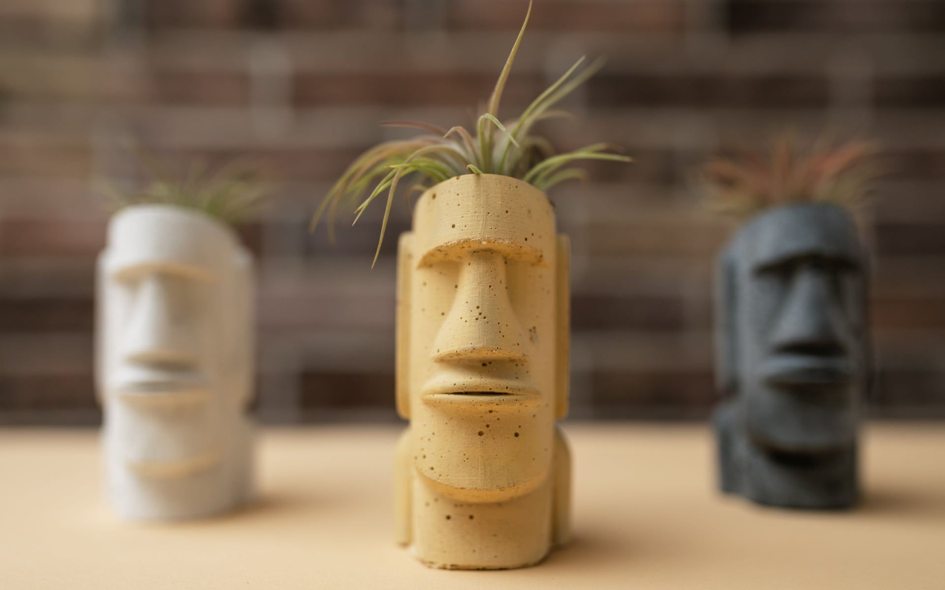 Drie 3D-geprinte plantenpotjes in de vorm van Moai-beelden