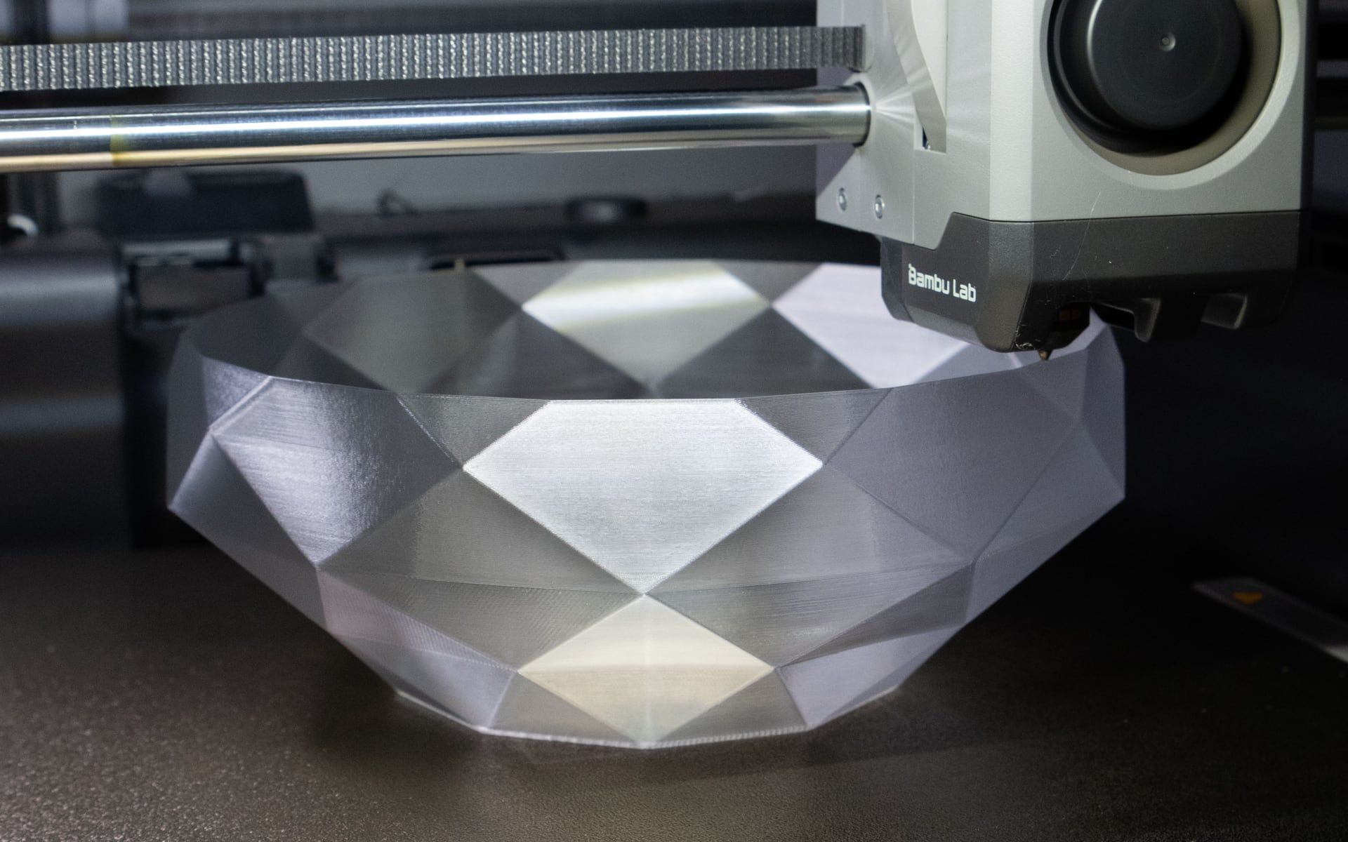 Een 3D-printer die een zilverkleurige schaal met facetten print